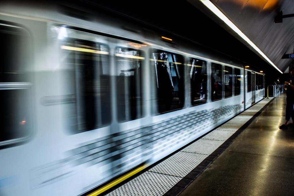 White LRT vehicle on an outdoor train station platform. 