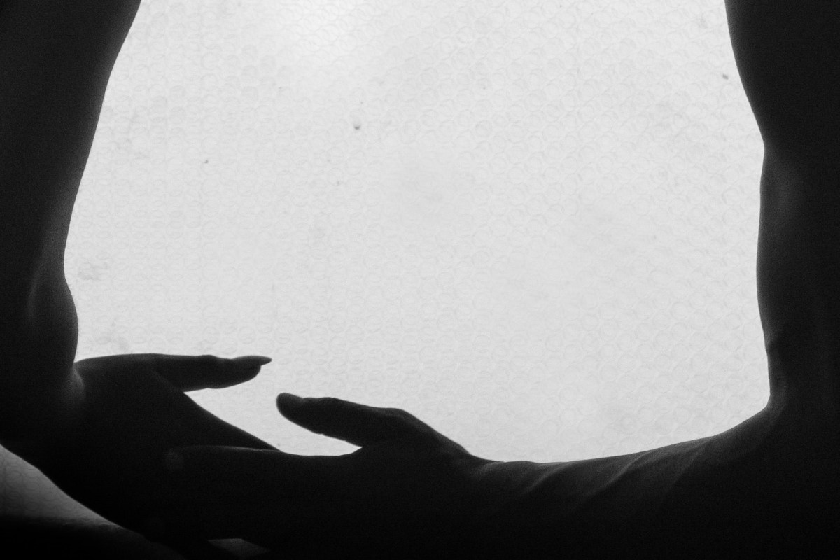 Black and white photo of a couple holding hands, photo focus on the torso, arms and hands.
