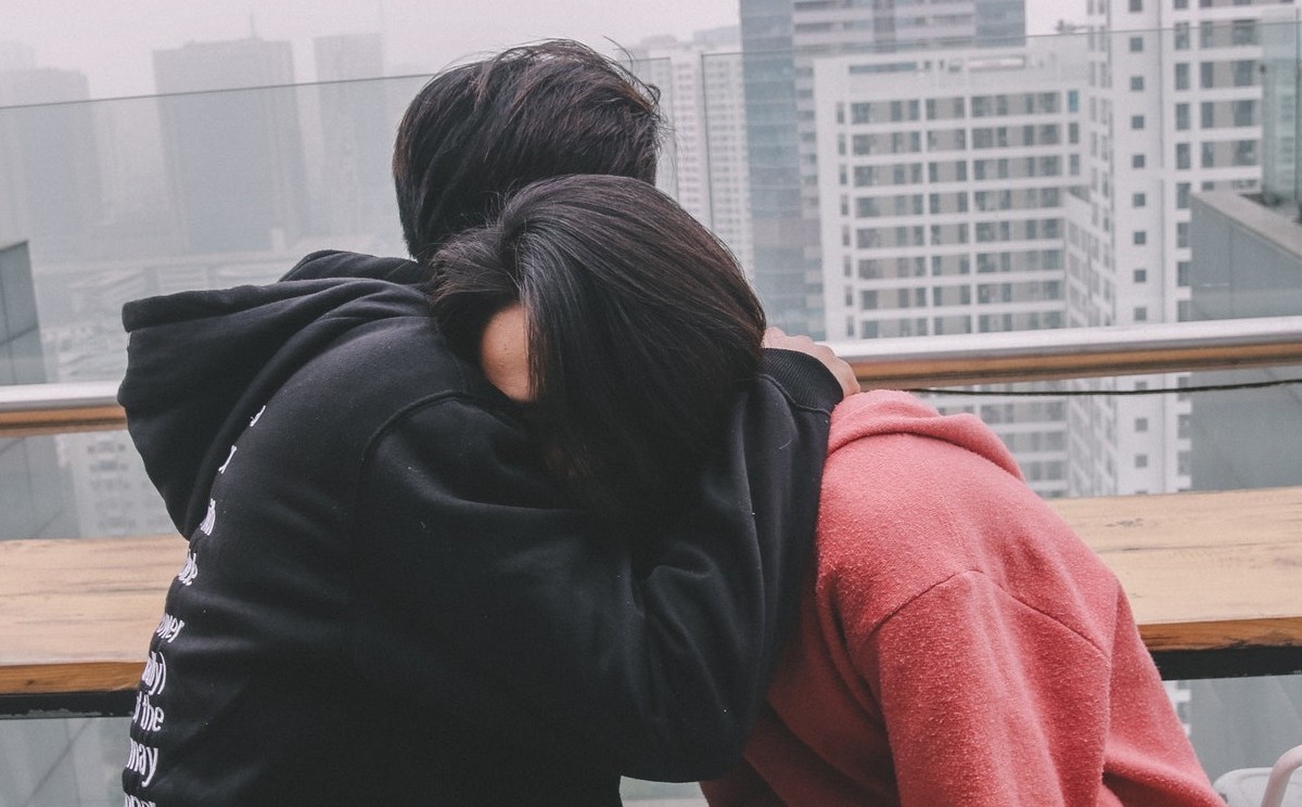 Man hugging woman, woman's head burried on his shoulder