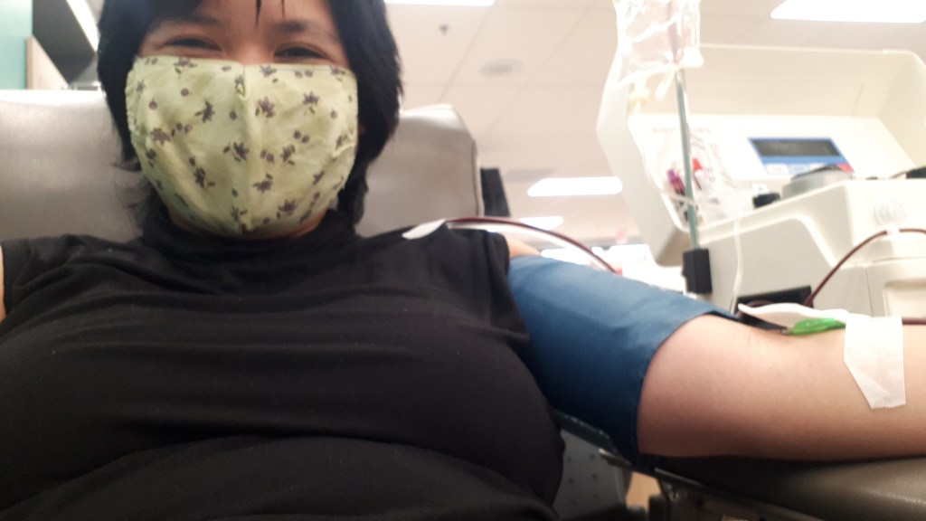Woman wearing a face mask while donating blood at a blood donation clinic. 