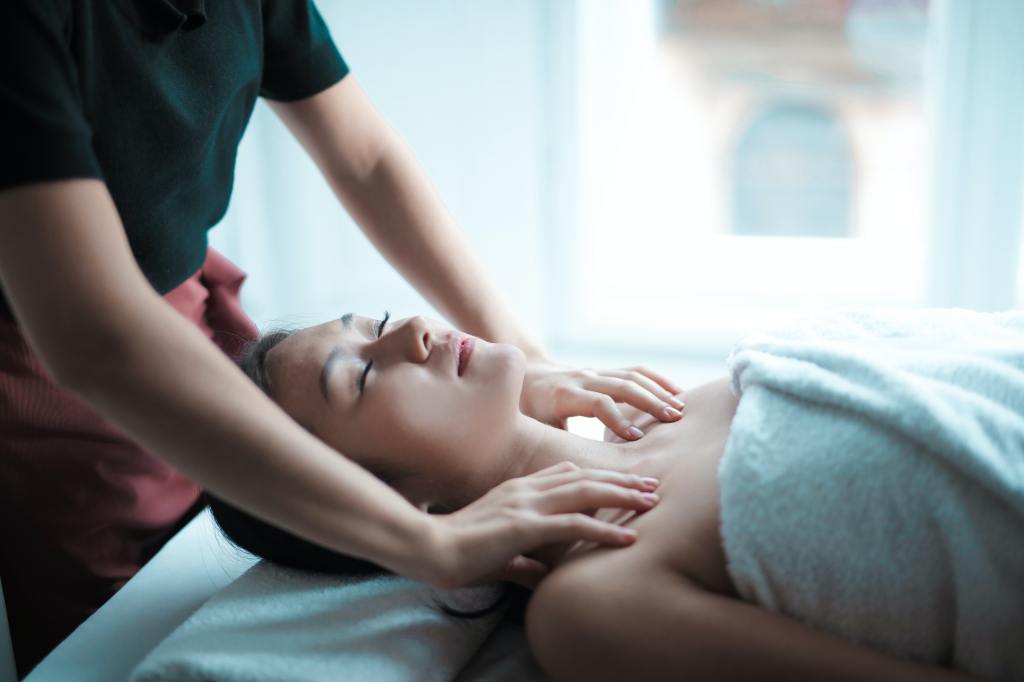 Closeup of a woman's face and shoulders, while lying on a massage bed getting a shoulder massage.
