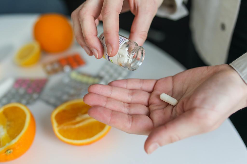 person's hand catching a medicine pill being poured out of the bottle. 